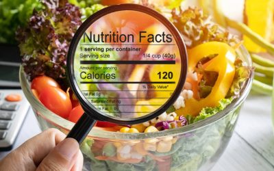 nutritional information concept. hand use the magnifying glass to zoom in to see the details of the nutrition facts from food , salad bowl